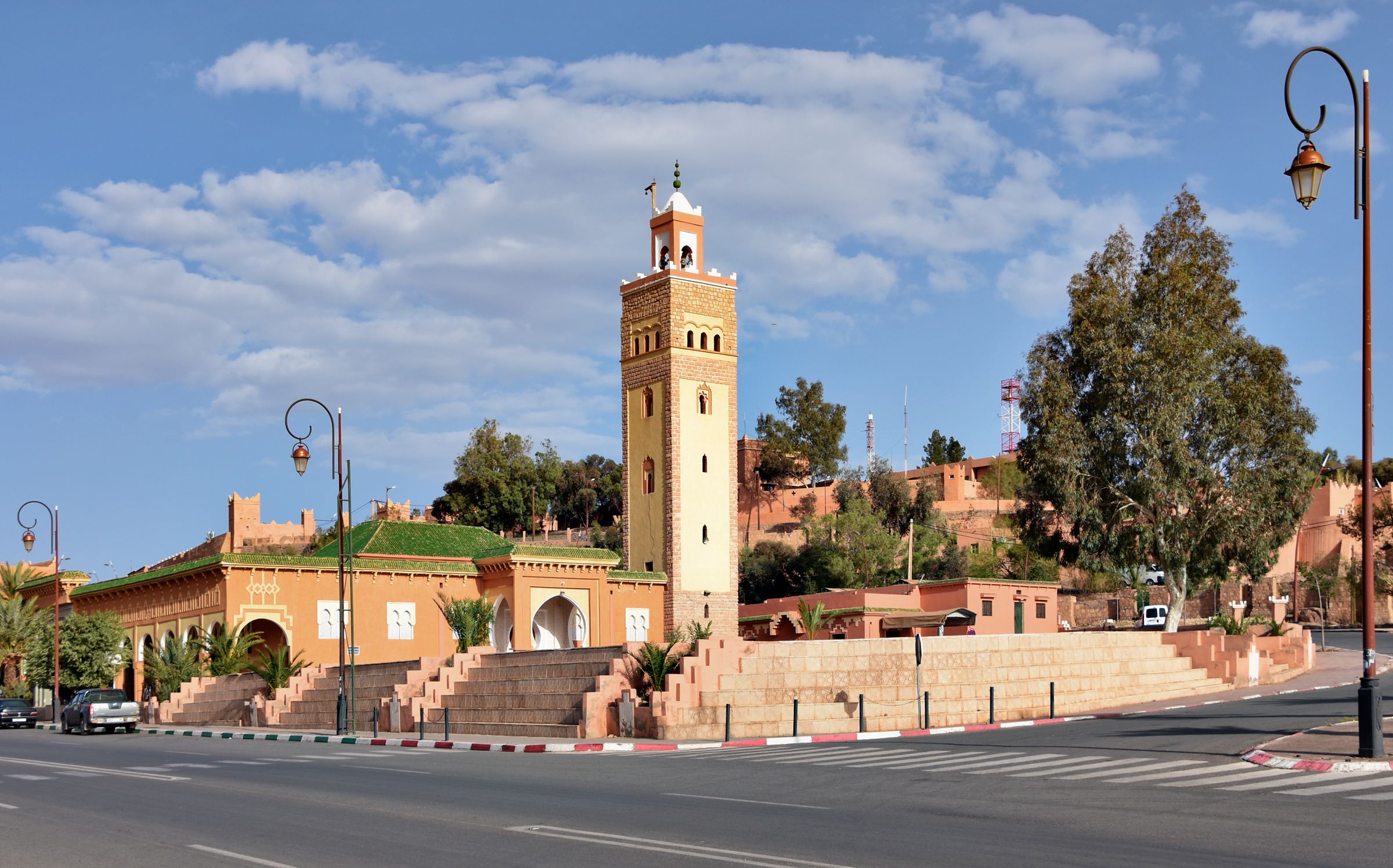 A mosque tower in Ouarzazate rising above the street under a blue sky